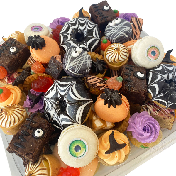 Halloween Themed Assorted Dessert Platter from Whippt Kitchen featuring spider web donuts, eyeball French macarons, spooky brownies, witch hat cupcakes and more.